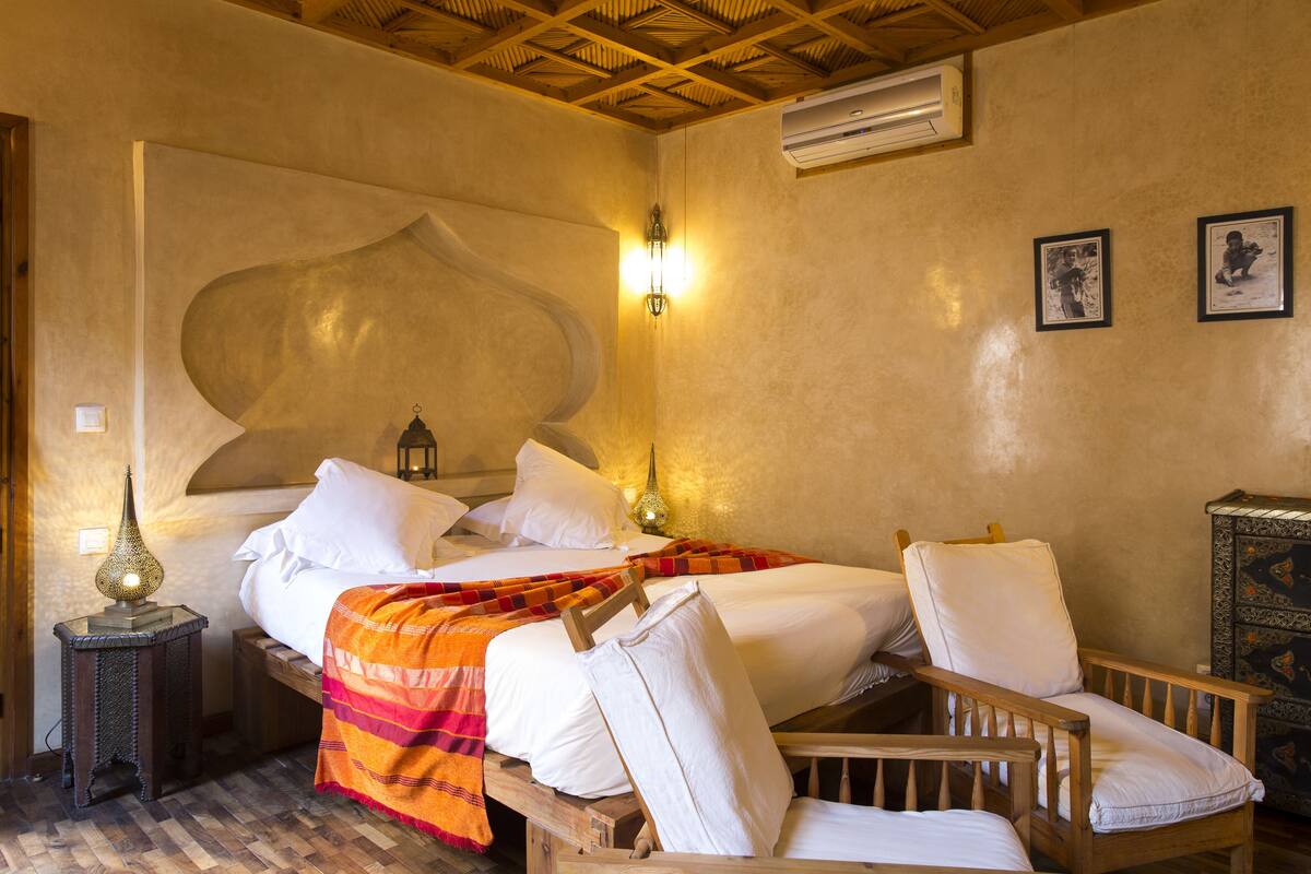 Un dormitorio con una cama grande, dos mesitas de noche, una butaca y un adorno en la pared.
