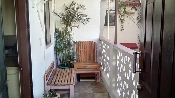 Ein schmaler Balkon mit einer Holzbank, einem Blumentopf und einer dekorativen Wandverkleidung.