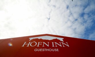 Logotipo de la casa de huéspedes Höfn Inn sobre un cielo nublado.