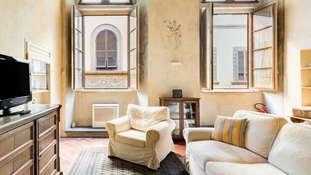 A cozy living room with a fireplace, two armchairs, a sofa, and a television on a wooden cabinet. - "Botticelli","Donatello"&"Dante"apartments by WP Relais in the heart of Florence (Firenze)