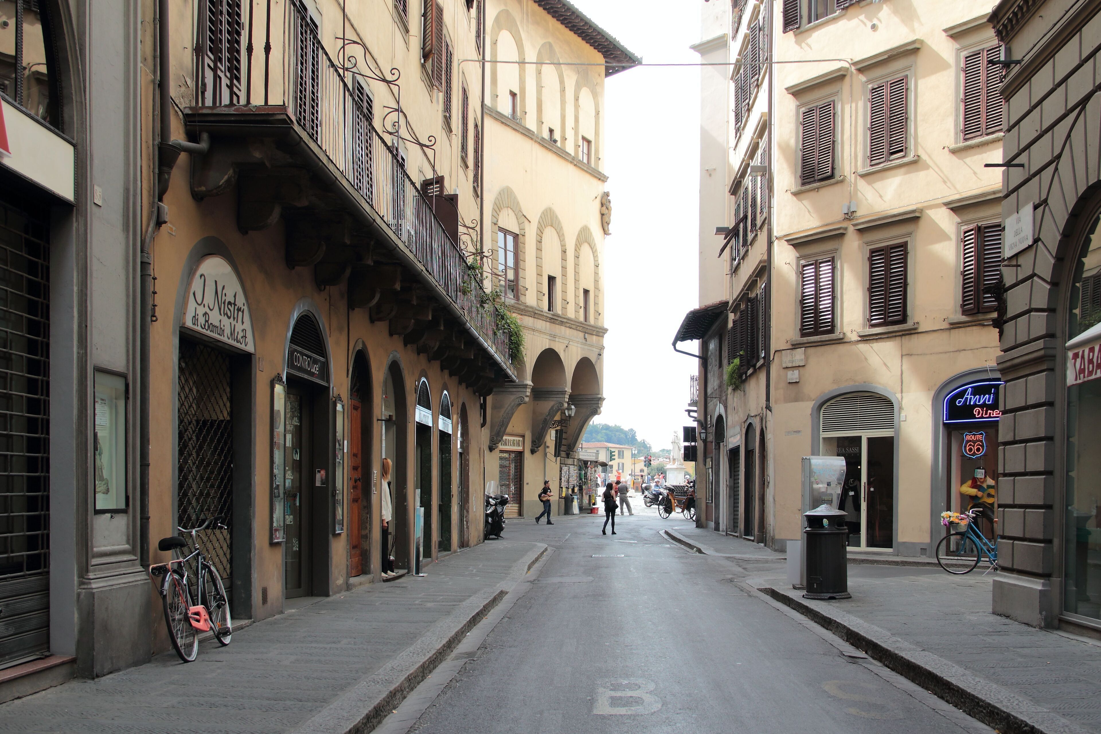 Una calle con edificios, una bicicleta y un contenedor de basura.