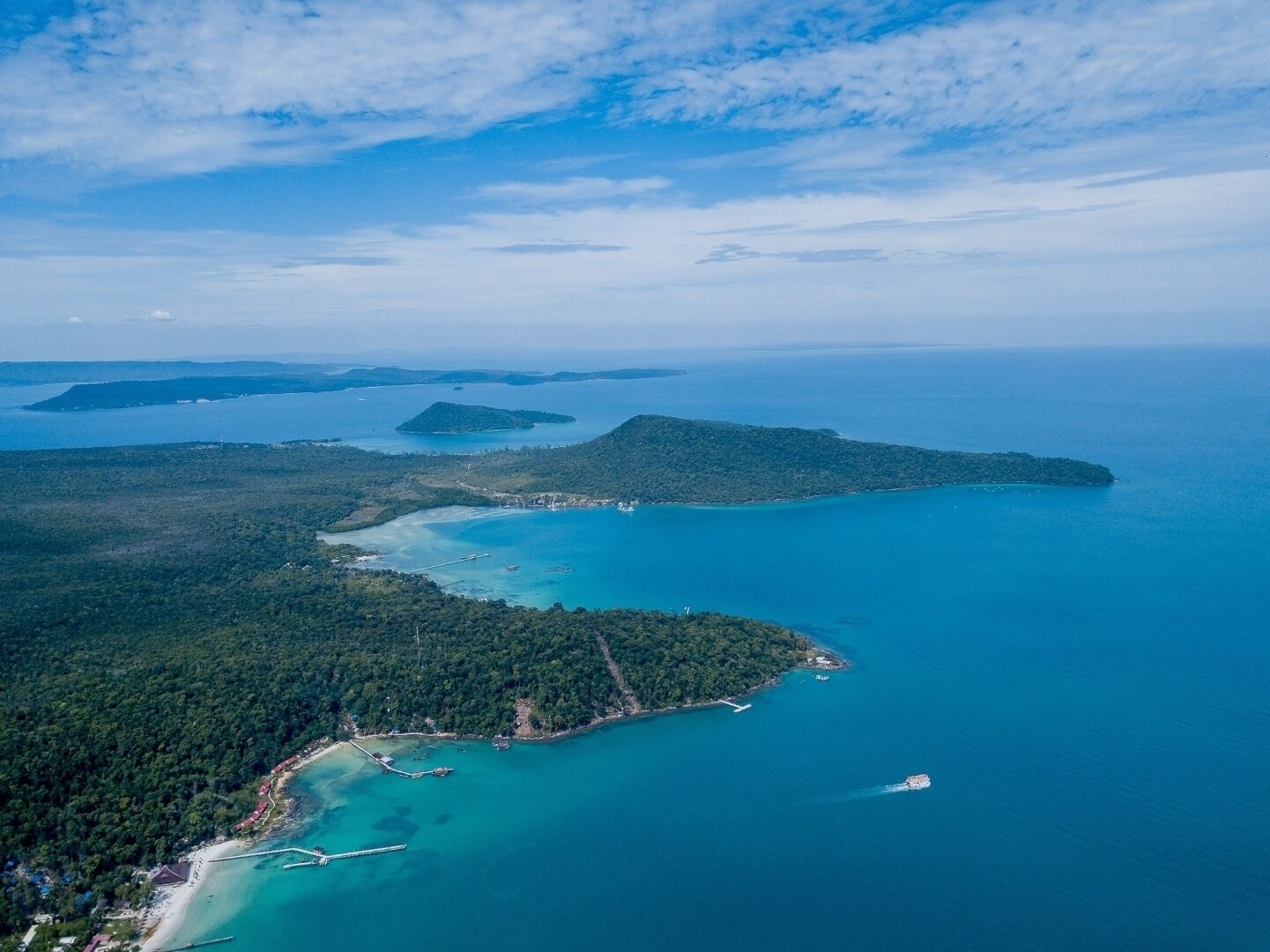 Eine Vogelperspektive einer Küstenlandschaft mit Strand, klarem, blauem Wasser und mehreren kleinen Inseln.