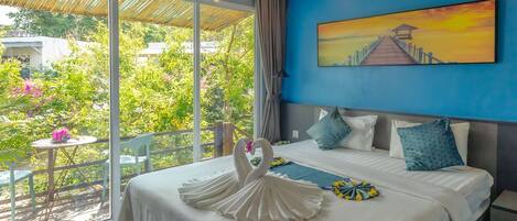 A hotel room with a bed, a painting of a pier, and a view of greenery outside.