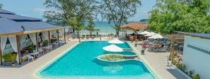 A pool area with lounge chairs and umbrellas, a covered seating area, and a view of the beach. - Sara Resort (Koh Rong Sanloem)