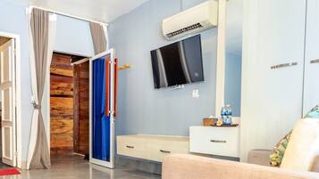 Una habitación de hotel moderna con una pared de acento de madera, un televisor de pantalla plana, un espejo grande y un sofá color beige.