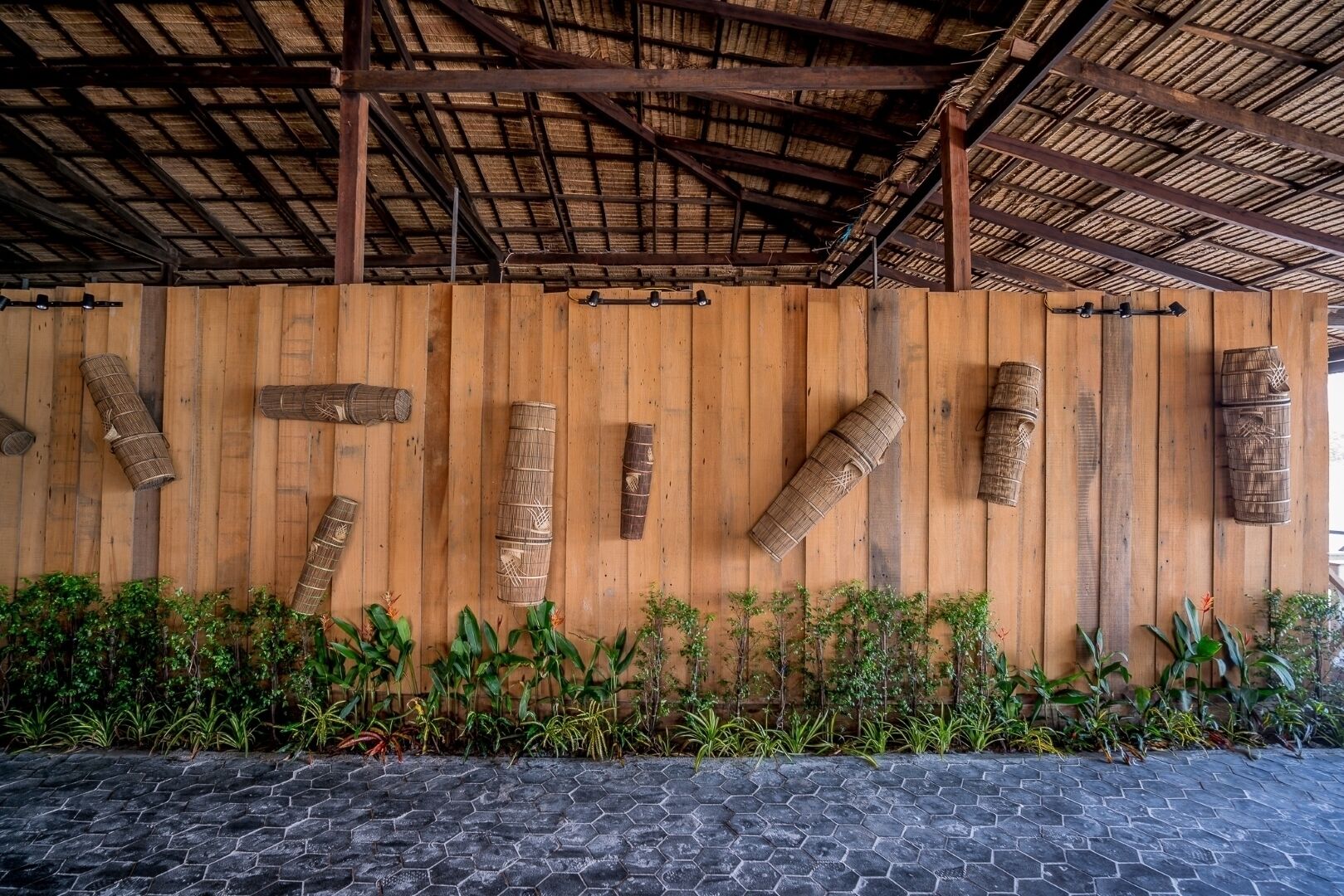 A wooden wall with woven baskets and a thatched roof structure.