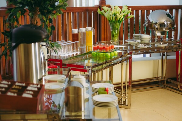 A buffet setup with various food items, beverages, and a decorative vase.