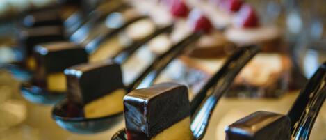 A dessert buffet with various sweets arranged on spoons.