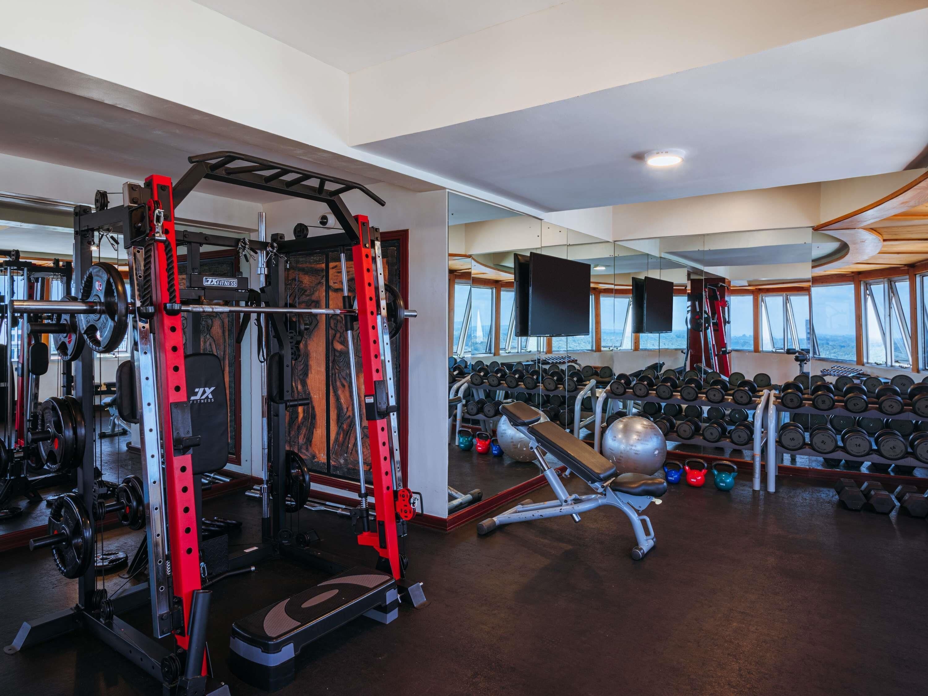 A gym with weightlifting equipment, dumbbells, and exercise balls.