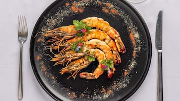 A black plate with grilled shrimp, garnished with parsley and red pepper flakes, on a white tablecloth.