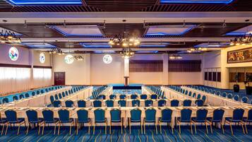 A conference room with a long table, blue chairs, and a patterned carpet.