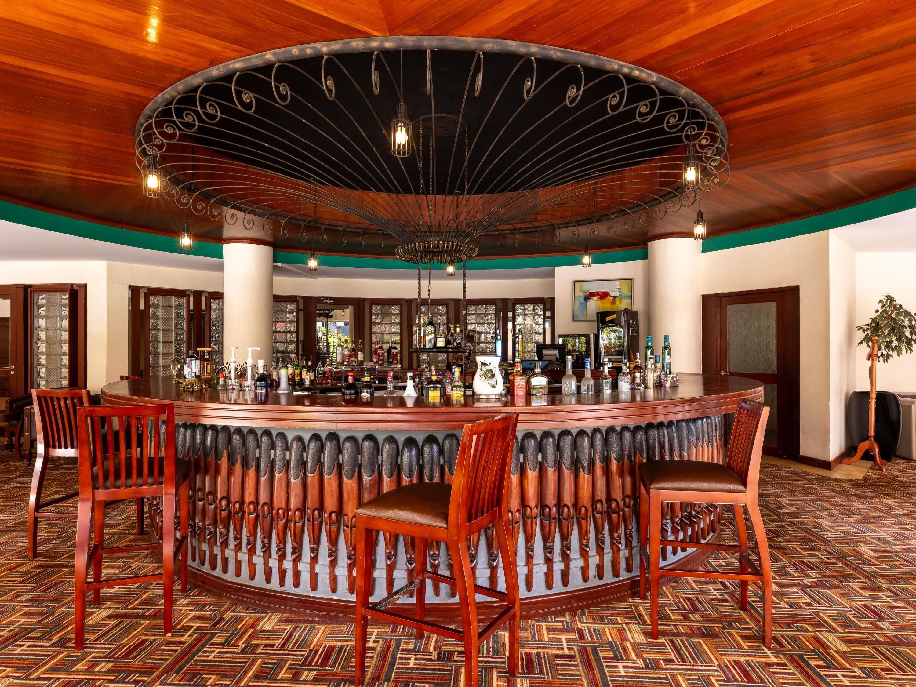A bar area with a circular wooden ceiling, a bar counter, and several wooden chairs.