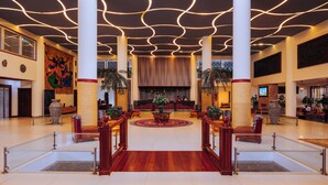 Un hall d’entrée spacieux, doté d’un tapis rouge central, de grandes colonnes et d’un design de plafond moderne.