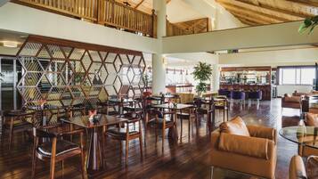 A spacious indoor area with wooden flooring, multiple seating arrangements, and a high ceiling with exposed beams.