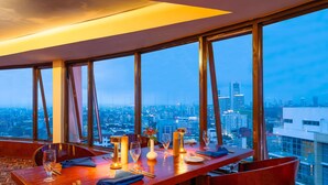 Un espace repas avec vue sur la ville, une longue table et des chaises.