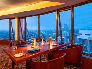 A dining area with a city view, a long table, and chairs. - Mövenpick Hotel & Residences Nairobi (Nairobi)