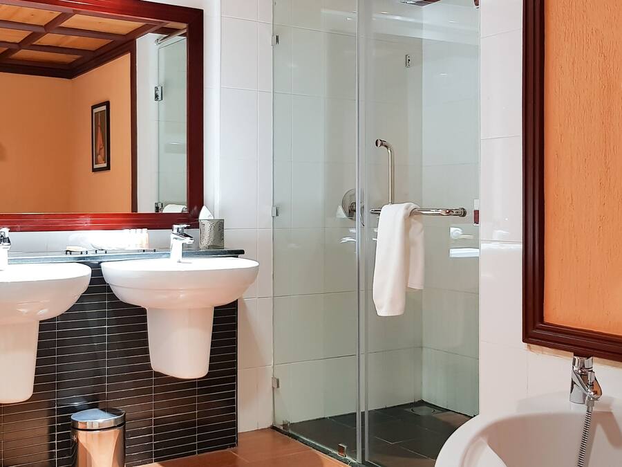 A bathroom with two sinks, a shower, and a toilet.