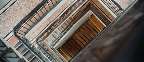 A multi-level interior with a central staircase, metal railings, and a patterned floor.