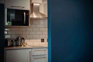 Una cocina con microondas, tostadora, hervidor y una campana extractora de acero inoxidable.