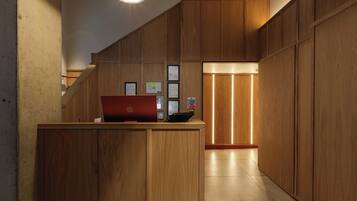 A wooden reception desk with a laptop, framed certificates, and a red telephone.