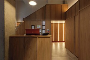 Un mostrador de recepción de madera con una computadora portátil, diplomas enmarcados y un teléfono rojo.
