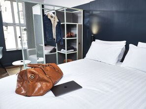 A hotel room with a bed, a laptop, and a brown leather bag.