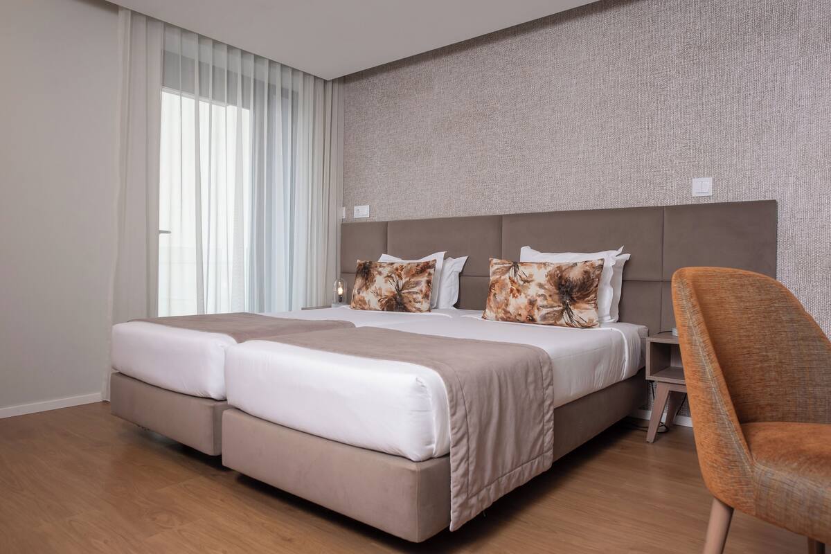 A modern hotel room with a large bed, a nightstand, and a chair.
