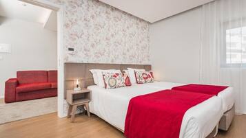 Un dormitorio moderno con una cama grande, un sofá rojo y una mesita de noche con una lámpara.