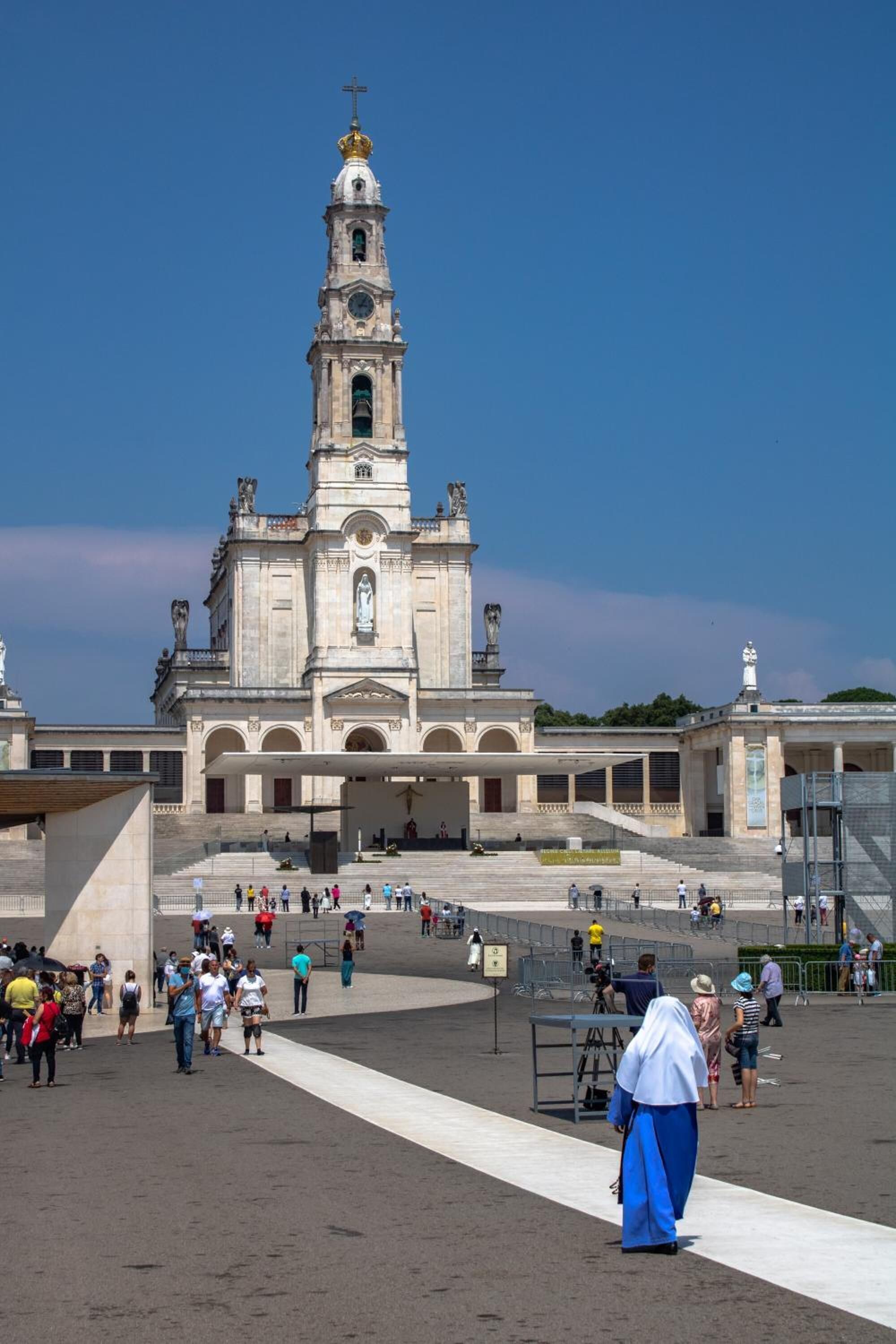 Una iglesia histórica con un alto campanario y una amplia plaza frente a ella.