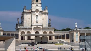 Una iglesia histórica con un alto campanario y una amplia plaza frente a ella.