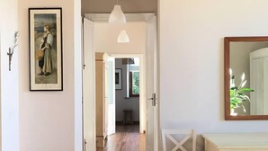 A room with a wooden floor, a white table, a framed painting on the wall, and a mirror on the right. - Villa Tavallini (Pollone)
