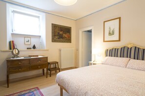 A bedroom with a bed, dresser, and a window.