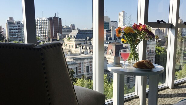 A city view from a balcony with a table featuring a drink, flowers, and a pastry. - Days Inn & Suites by Wyndham La Plata (La Plata)