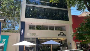 A modern building with a glass facade, a sign for 'Host' hotel, and 'Days Inn' across the street. - Days Inn & Suites by Wyndham La Plata (La Plata)