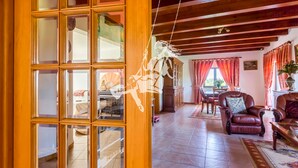 Ein geräumiges Wohnzimmer mit Holzboden, einem Essbereich mit Tisch und Stühlen und Blick durch eine Glastür.