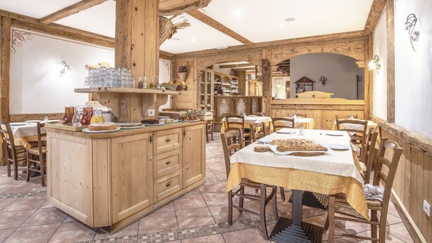 A rustic dining area with wooden furniture, a central island with kitchenware, and a view into the kitchen. - Antica Residenza de Poda (Contà)