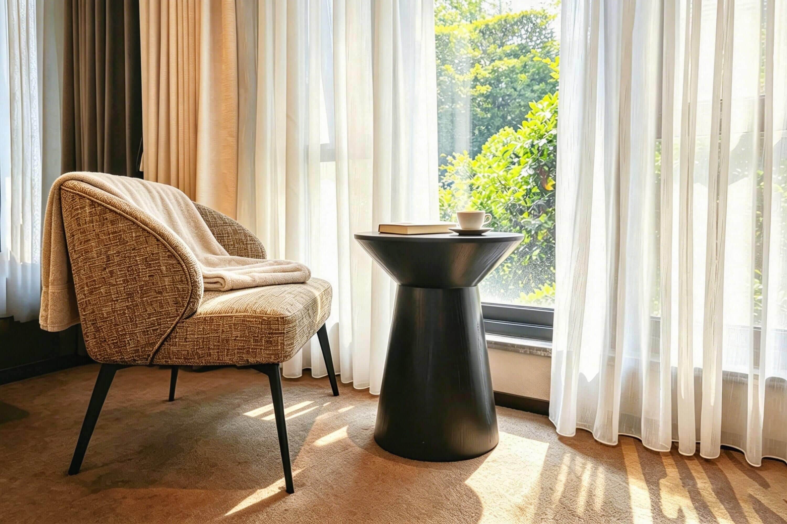 A room with a chair, a table, and a window with curtains.