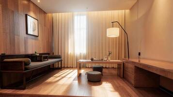 Una sala moderna con piso de madera, un sofá, una mesa y una lámpara.