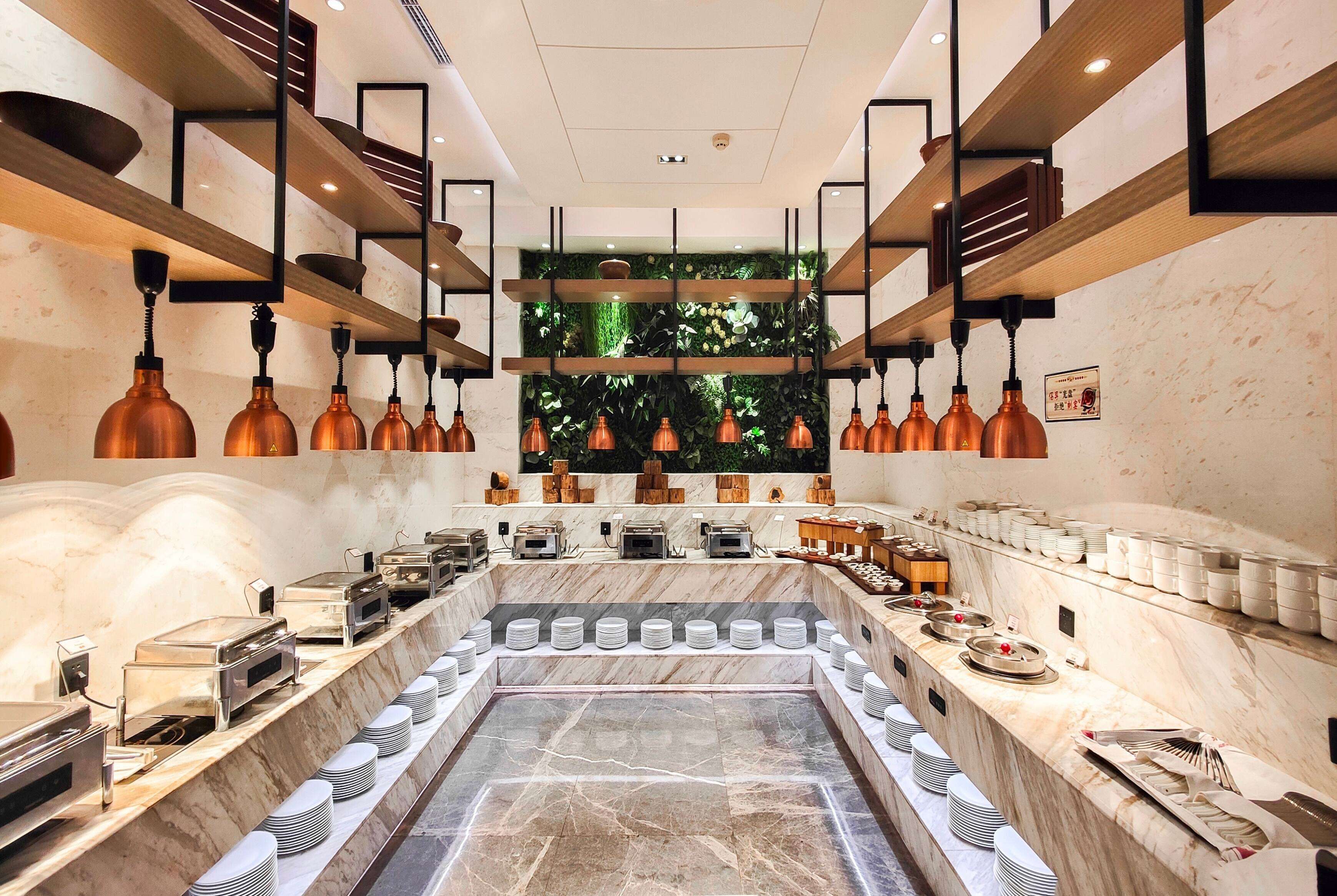 A buffet setup with multiple serving stations, a central marble counter, and overhead lighting fixtures.