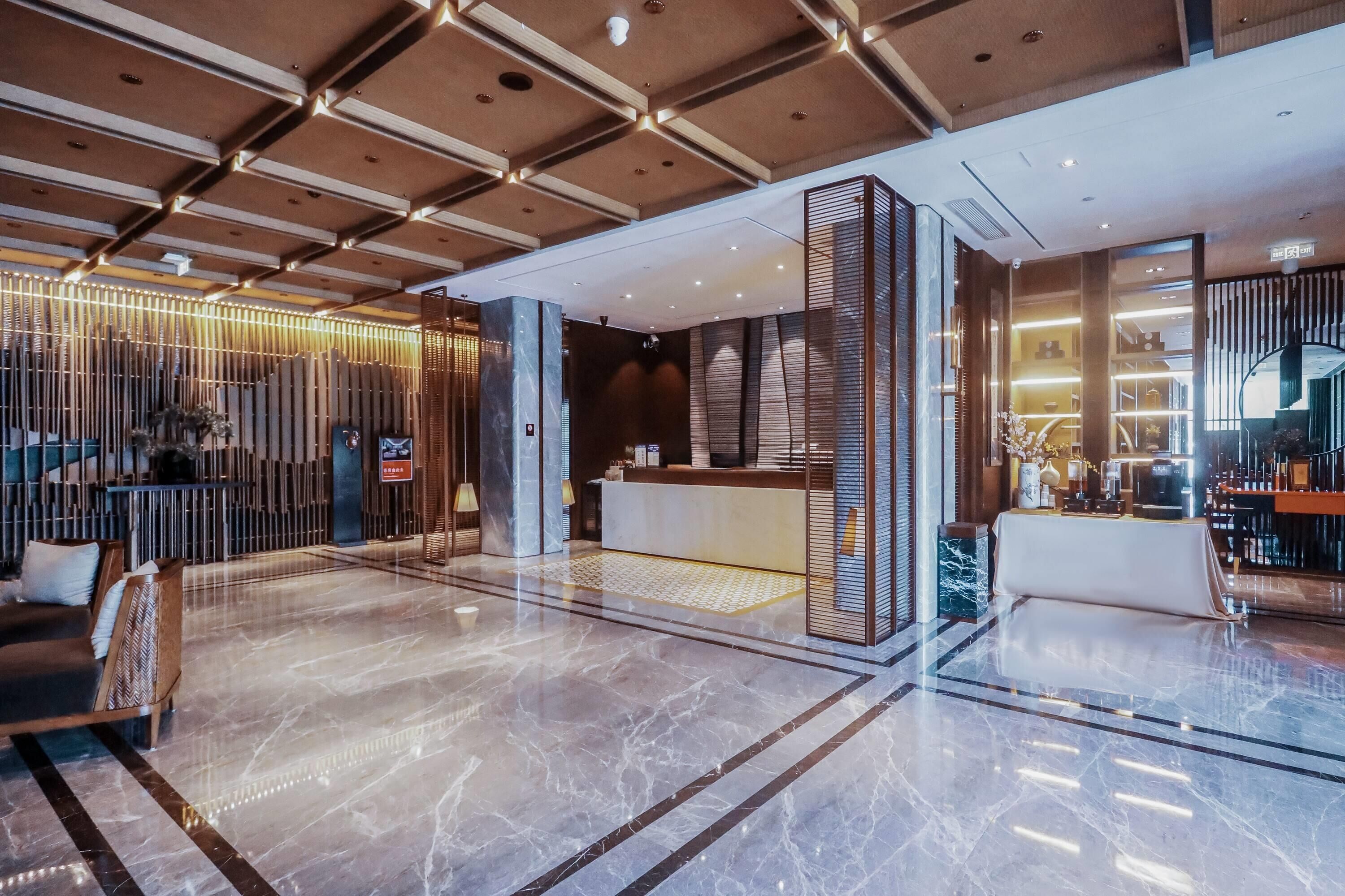 Un vestíbul modern amb taulell de recepció, zona de seients i una paret decorativa amb elements verticals.