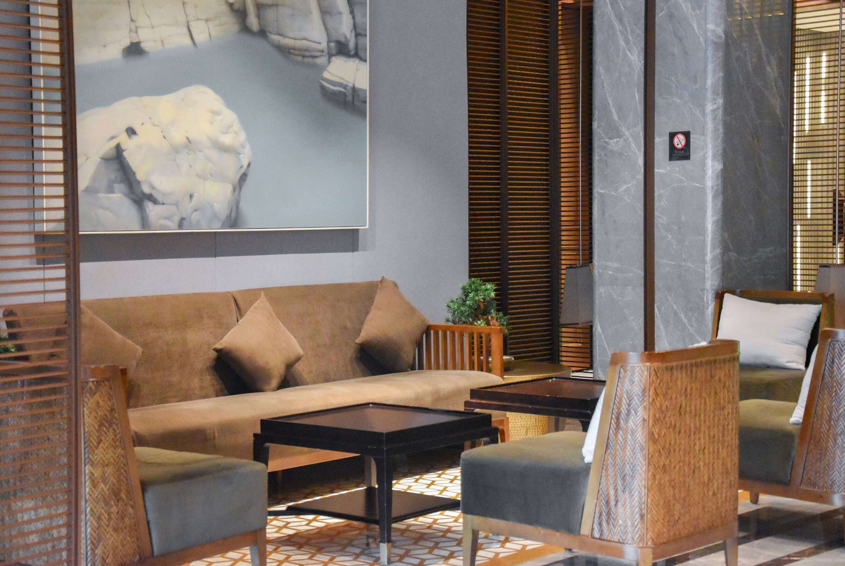 A modern lobby with a sofa, armchairs, a coffee table, and a large abstract painting on the wall.