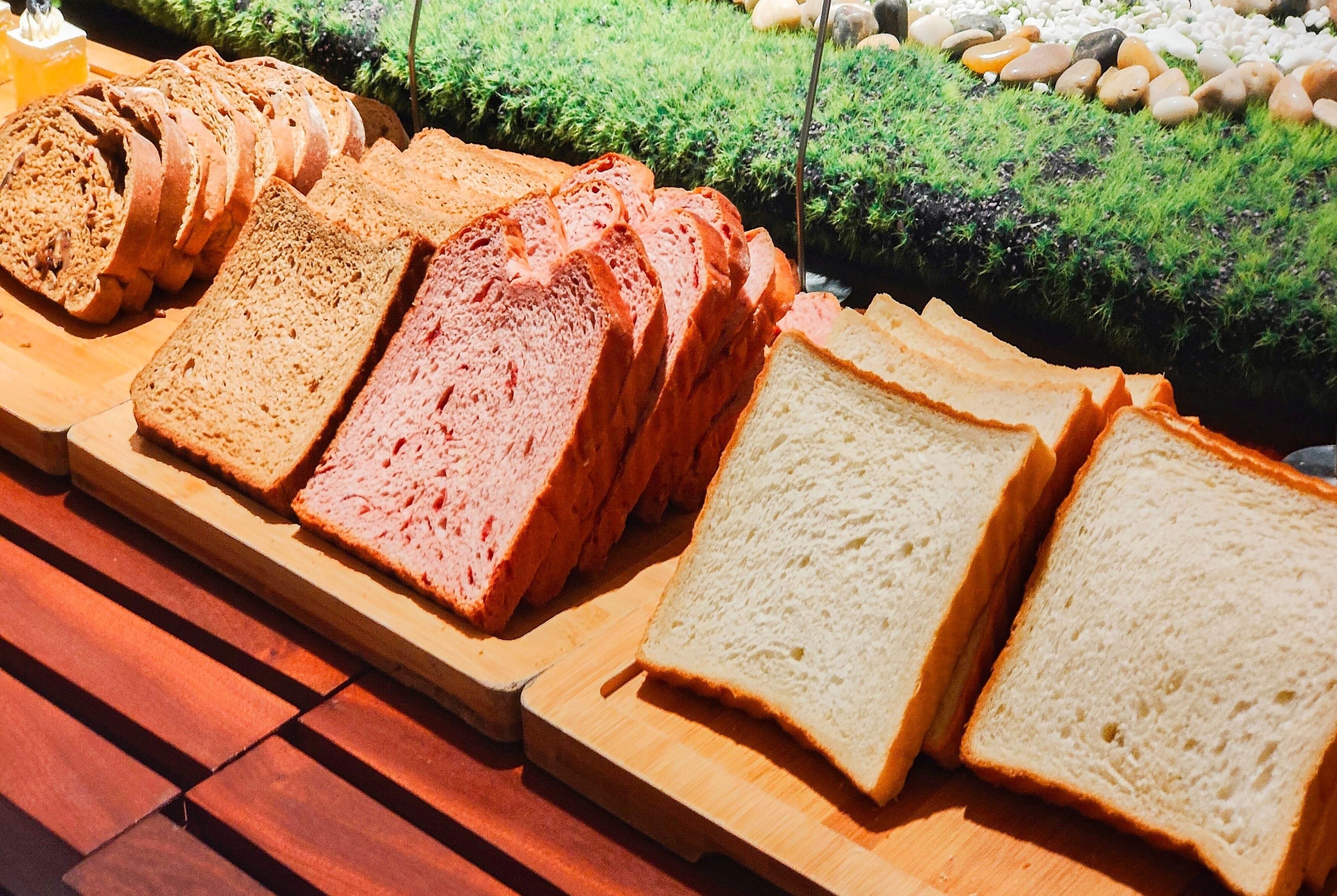 A variety of sliced breads on a wooden board.