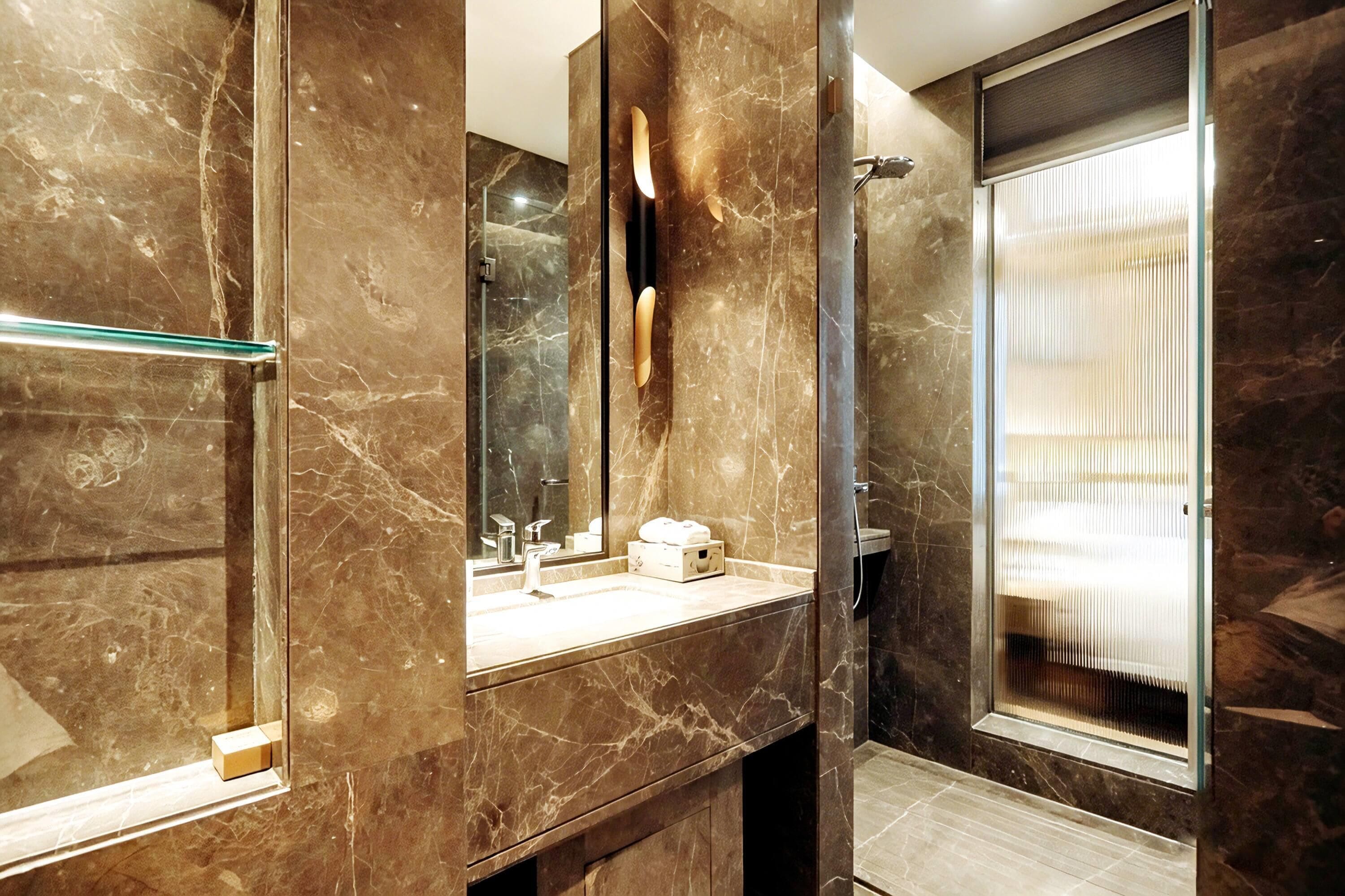 Une salle de bain moderne avec un meuble-lavabo en marbre, une cabine de douche en verre et un grand miroir.