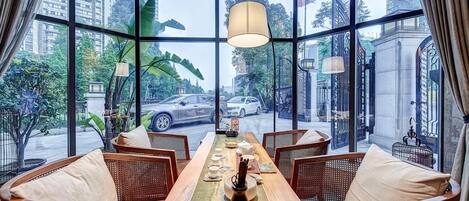 Un comedor con una larga mesa de madera, sillas de mimbre y vistas a la ciudad a través de amplios ventanales.