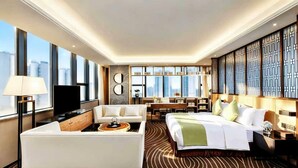 A modern hotel room with a sofa, bed, TV, and city view. - Ramada Leshan (Leshan)