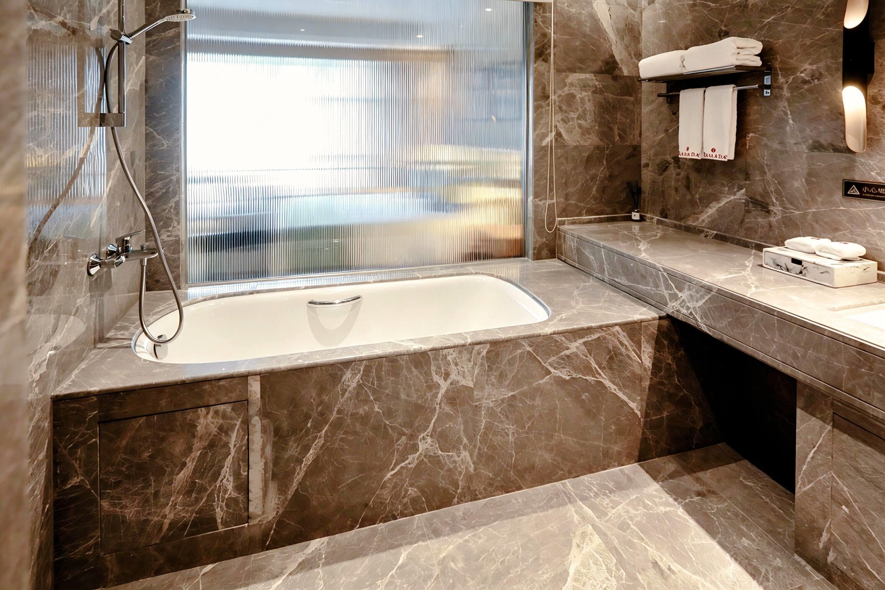 Un baño moderno con lavamanos de mármol, ducha con cerramiento de vidrio y toallero con toallas dobladas con cuidado.