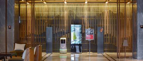 A modern lobby with a reception desk, seating area, and a decorative wall with vertical elements.