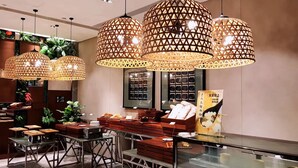 A modern interior with hanging wicker lamps, a glass display case, and a counter with baked goods. - Ramada Leshan (Leshan)