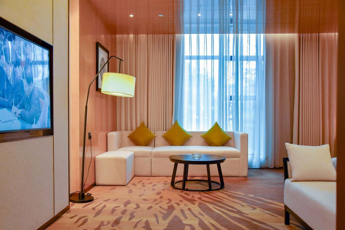 A modern hotel room with a sofa, a coffee table, and a floor lamp.