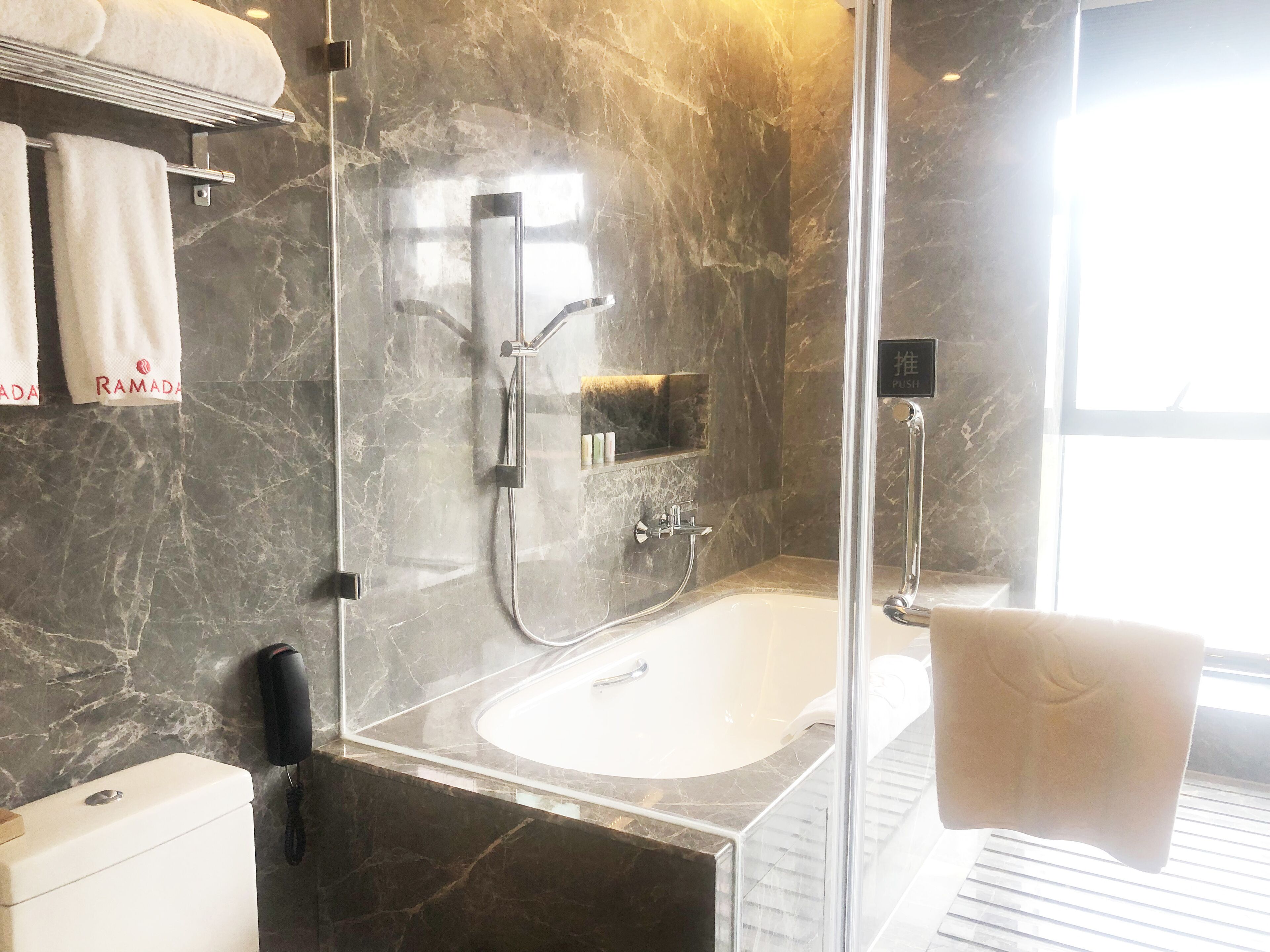 A modern bathroom with a glass-enclosed shower, a white bathtub, and a toilet.